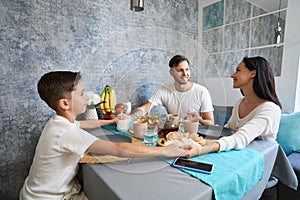 Family holding hands while having dinner together at table