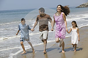 Family Holding Hands While Running On Beach