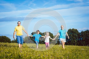 Family holding hands running over meadow