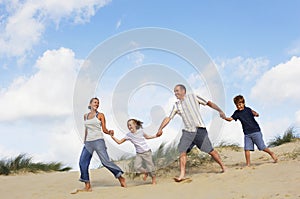 Family Holding Hands And Running On Sand