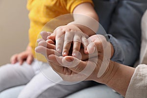 Family holding hands together on beige background, closeup