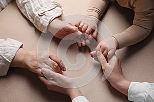 Family holding hands together on brown background, above view