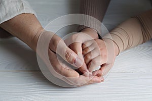 Family holding hands together at white wooden table, closeup