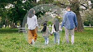 Family, holding hands and walking in park from the back with love and care together in nature. Travel, insurance and