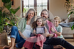 Family holding smart thermostat, adjusting, lowering heating temperature at home. Concept of sustainable, efficient, and