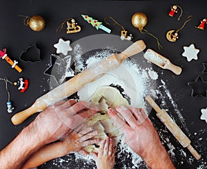 Top view of fathers and kids hands making Christmas cookies on b