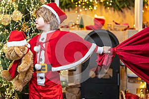 Family holiday. Boy child play near christmas tree. Wish to meet santa claus. Santa Claus helper carrying big bag full