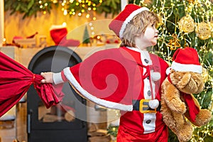 Family holiday. Boy child play near christmas tree. Wish to meet santa claus. Santa Claus helper carrying big bag full