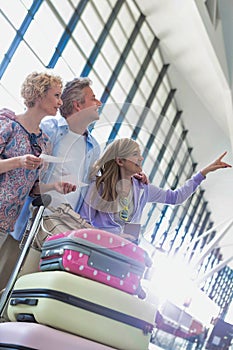 Family on holiday looking at their flights on monitor in airport