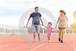 Family holiday Parents take their daughters to walk and run. And playing exercise at the stadium happily and having fun While