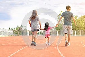 Family holiday Parents take their daughters to walk and run. And playing exercise at the stadium happily and having fun While