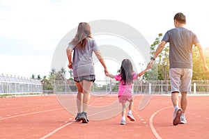 Family holiday Parents take their daughters to walk and run. And playing exercise at the stadium happily and having fun While