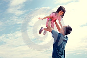 Family holiday The sky is bright. Father and daughter are playing outdoors happily. Father carried his daughter and lifted him up