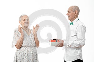 Family, holidays, christmas, age and people concept - happy senior couple with gift box at home, dressed in white closes
