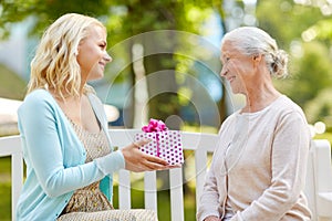 Daughter giving present to senior mother at park