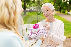 Daughter giving present to senior mother at park