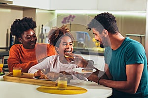 Family at home eating breakfast in kitchen together