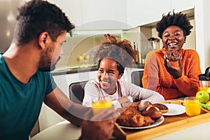 Family at home eating breakfast in kitchen together, having fun