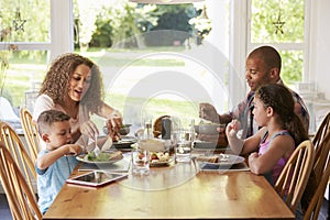 Family At Home Eating Meal In Kitchen Together