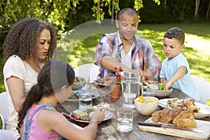 Family At Home Eating Outdoor Meal In Garden Together