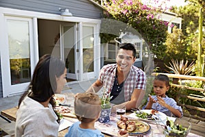 Family At Home Eating Outdoor Meal In Garden Together