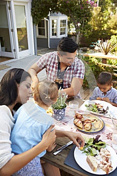 Family At Home Eating Outdoor Meal In Garden Together