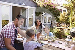 Family At Home Eating Outdoor Meal In Garden Together