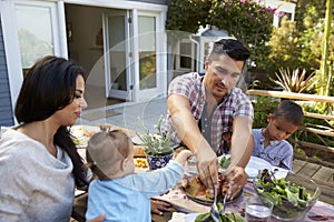 Family At Home Eating Outdoor Meal In Garden Together