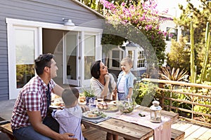 Family At Home Eating Outdoor Meal In Garden Together