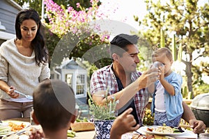 Family At Home Eating Outdoor Meal In Garden Together