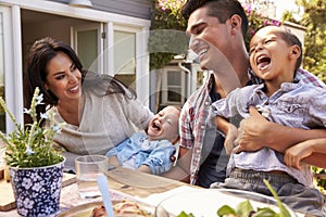 Family At Home Eating Outdoor Meal In Garden Together