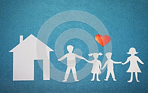 Family and home love concept. Paper house and family on blue textured background. Red heart over family and home silhouettes.