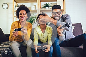Family at home sitting in sofa couch and playing console video games together