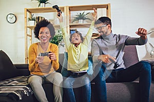 Family at home sitting in sofa couch and playing console video games together