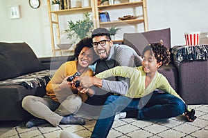 Family at home sitting in sofa couch and playing console video games together