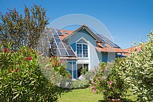 Family home with solar cells at the roof, backyard garden with mediterranean plants