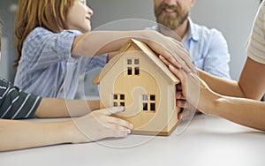 Family with house model illustrating concept of buying new home, mortgage or insurance