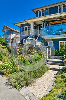 Family house with weedy front yard on blue sky background