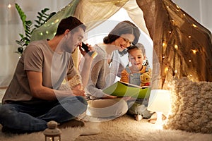 Happy family reading book in kids tent at home