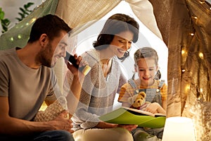 Happy family reading book in kids tent at home