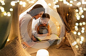 Happy family reading book in kids tent at home