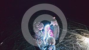 Family is ice skating night, make selfie. Mother, father, daughter and son riding together on ice in cracks. Outdoor