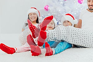 Family idyll, young parents and children in christmas morning sitting close to xmas tree at home in living room