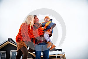 Family including father, mother, little daughter in yellow, red and brown dress on a walk in winter. A man and woman