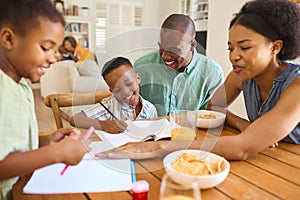 Family Indoors At Home Helping Children With Homework With Grandparents In Background photo