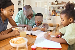 Family Indoors At Home Helping Children With Homework With Grandparents In Background photo