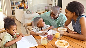 Family Indoors At Home Helping Children With Homework With Grandparents In Background photo