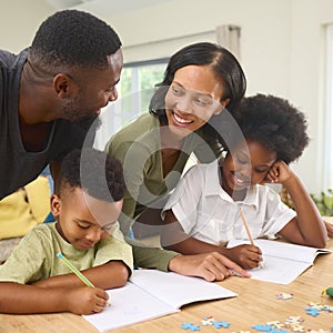 Family Indoors At Home With Parents Helping Children With Homework Sitting At Table photo