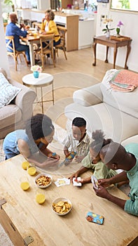 Family Indoors Sitting Around Table At Home Playing Card Game Together photo