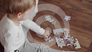 Family, innocence, infant concepts - little smart boy 2 years old makes puzzles on floor at home
